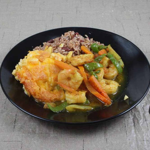 Island Flavors' Jamaican curry shrimp with rice and peas, and fried plantains on a black plate.
