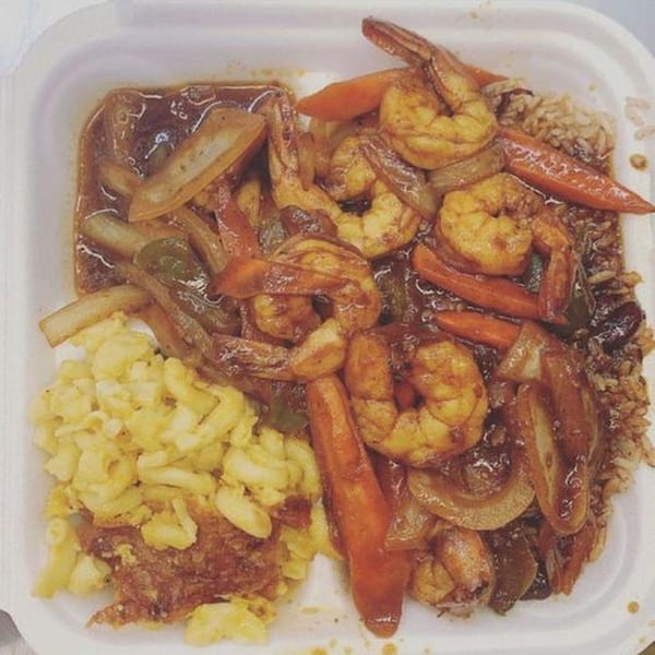 Island Flavors' Jamaican shrimp with rice, vegetables, and macaroni and cheese in a takeout container.