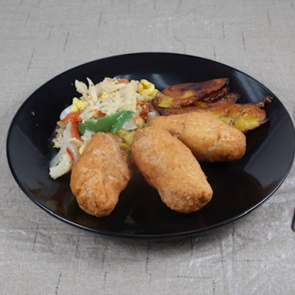 A Jamaican breakfast plate with ackee and saltfish, fried dumplings, and ripe plantains.